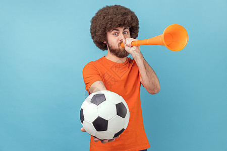 男人庆祝最喜欢的足球队的胜利 吹喇叭和球在手图片