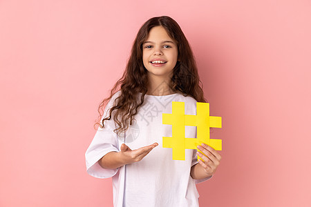 小女孩展示黄色大标签符号 在摄影机 博客和儿童内容上微笑 (笑声)图片