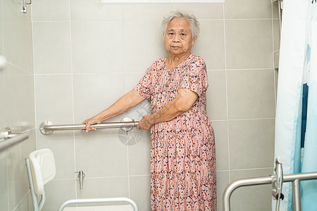 亚洲老年妇女患者在护理医院病房使用厕所浴室手柄安全 健康强大的医疗理念医院浴缸事故潮红帮助照顾者金属淋浴座位苗圃图片