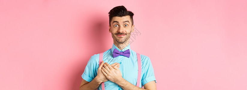 留着小胡子 穿着衬衫和领结 手牵着心 微笑着表示感谢 站在粉红色背景上说谢谢的快乐年轻人胡须工作室促销吊带裤办公室商业男人成人发图片