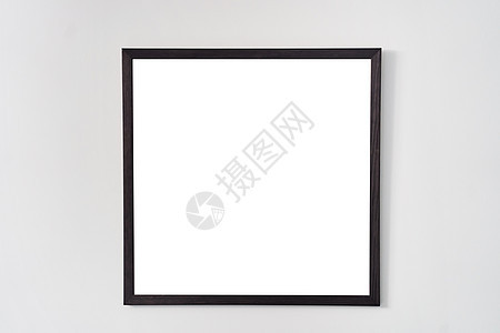 白色墙上挂有黑边框的空平方相片框图片