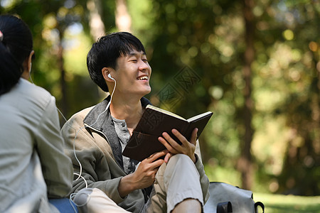 可爱的年轻夫妇坐在一起坐在公园里 用耳机听音乐和听音乐图片