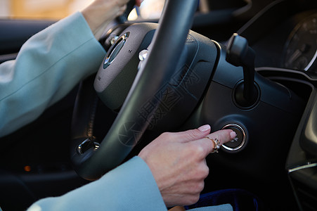 在现代豪华轿车上按下启动停动引擎按钮 驾驶汽车概念的近身女性手指图片