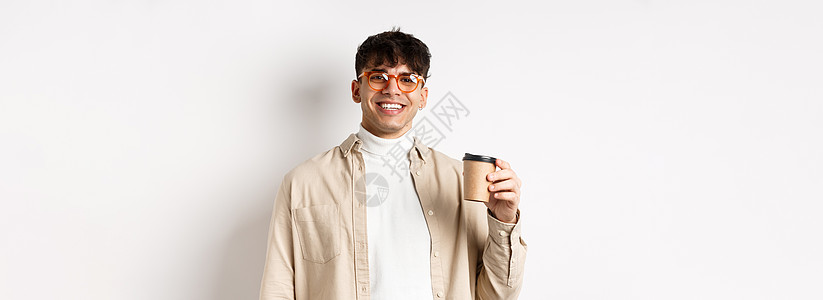 真实的人 快乐的年轻人用纸杯喝咖啡 在最喜欢的咖啡馆点外卖 微笑着看着相机 白色背景咖啡店咖啡饮料生活男人商业成功成人潮人发型图片