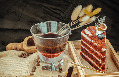 浓缩风味糖浆混合咖啡和新鲜牛奶在透明玻璃杯底部与一块红色天鹅绒蛋糕一起放在木菜板上砧板芳香饮品美食饮食背景饮料美味酒精享受图片