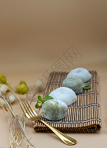 绿色茶叶和红豆达福库服务 在橙色背景的竹制地皮上配有铜叉薄荷叶营养品美食甜食早餐烹饪甜点年糕作品美味图片