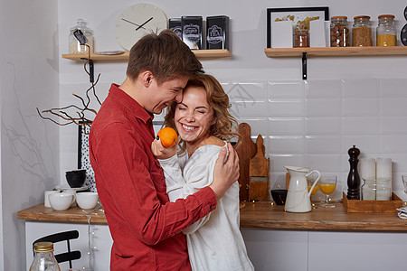 坐在厨房的一对快乐的小情侣互相拥抱 他们享受着时光相聚家庭咖啡丈夫成人午餐男性早餐男人女士乐趣图片