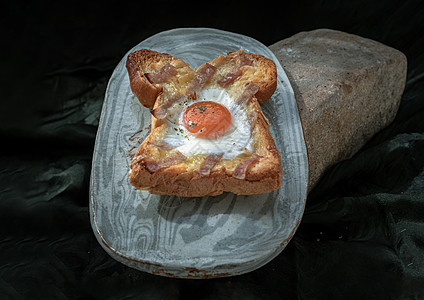 黑底陶瓷盘上的烤培根和奶酪烤面包里自制的炸鸡蛋背景美食奶油甜点食物深色蛋黄岩石糕点石头图片
