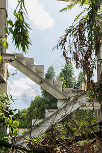 白铁楼梯或白钢楼梯 废弃建筑废墟中的白金属楼梯随着时间的推移以及结构元素和废墟的可见部分而恶化螺旋景观绿树建筑学损害房子金属艺术图片