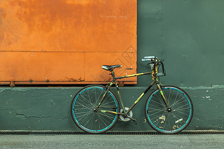 一辆自行车在钢橙门前 有绿墙的仓库绿化建筑运输建筑学框架山地街道车轮潮人旅行图片