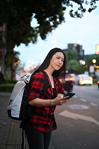 年轻亚裔女性在城市路上等待出租车 在路上搭乘计程车图片