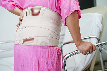 身穿有行尸弹性支撑带的亚洲高年级疼痛背部诊所肌肉腰部病人背痛痛苦手势老年骨科护士图片