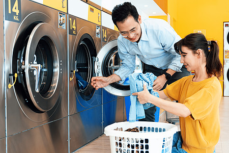 亚洲人使用合格的洗衣机 在公共房间里男人洗衣店篮子自助女士硬币垫圈女性洗涤剂服务图片