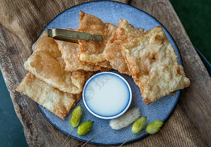 自制的甜脆泰式煎饼在陶瓷板上配有甜奶粉早餐午餐麻布美食盘子珠子面包干花营养甜点图片