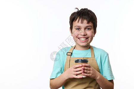 身着蓝色T恤衫和美食厨师围裙的英俊 微笑着笑脸的前童 拿着一张生态纸咖啡杯外送咖啡图片
