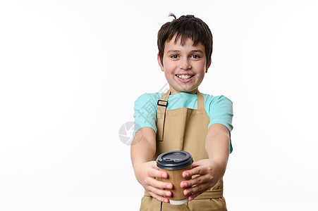 可爱笑笑的十几岁男孩 在美食大厨围裙上 分发生态纸板杯 和香味外送咖啡相机图片