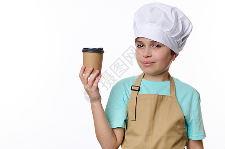 穿着厨帽和美食围裙的英俊十几岁男孩 在生态纸杯中出售热饮料茶图片