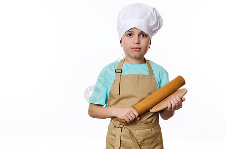 在英俊十几岁的男孩的白色背景上单独画像 一位用木板和滚动针制成的厨师美食器图片