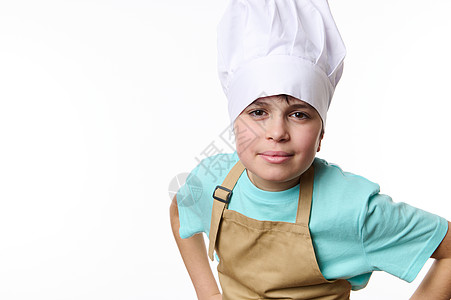 白色的孤立肖像 一名戴厨帽和围裙 手握腰带 笑着看着照相机的少年图片