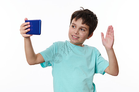 穿着蓝色T恤 使用智能手机 微笑和向移动电话打声招呼的快乐友好少年男孩 (笑声)图片