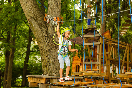 可爱的小女孩在温暖阳光明媚的夏日 享受她在攀登冒险公园的时间森林行动冒险喜悦活动学校耳环绳索娱乐女孩图片