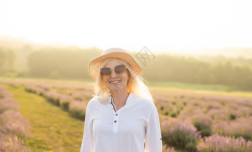 穿着草帽的金发年轻女旅行者 在熏衣草田里 围着紫色花朵旅游稻草女性游客卷曲蓝色女孩天空时尚场地图片