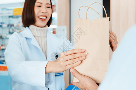 附属药剂师将合格的药品交给药店的顾客微笑病人出纳员架子服务工作零售店铺女士外套图片