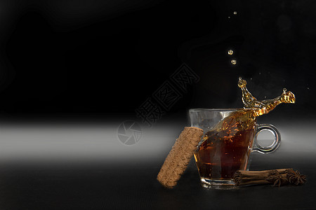 玻璃杯中的黑茶 在黑色背景上孤立的黑茶杯中喷洒 并配有美味饼干 复制空间去毒健康药品图片