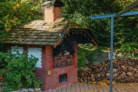 村子里的一个旧炉子和柴火 户外在秋天的老石壁炉 有木头的传统砖烤箱烘烤欧洲室外的面包图片