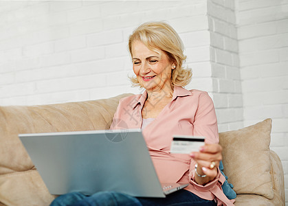 高级快乐老年妇女笔记本电脑在线购物信用卡电子商务订购订单购买无线账单商务图片