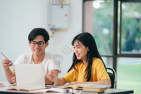 一个亚裔学生正在阅读书本和学习 一起教书学校教育导师同学教学技术讨论团队项目咨询图片