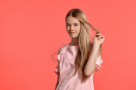 演播室肖像 一个美丽的女孩金发少女 穿着玫瑰色的T恤 在粉红色的背景运动衫学生成人金发女郎缠绕孩子工作室潮人女士情怀图片