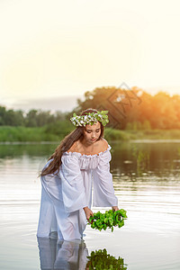 穿着白色连衣裙的女人在水中 头戴花圈的艺术女人在河中 她头上的花环 斯拉夫传统和异教装饰品魅力圆圈女性女子背景水仙女精神绿色冒充图片