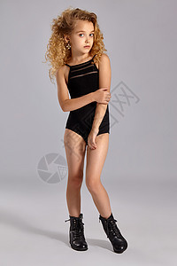 穿着黑色运动泳衣和灰色背面靴子的漂亮女孩体操运动员乐趣女性泳装耳环孩子生活发型运动装鞋带童年图片