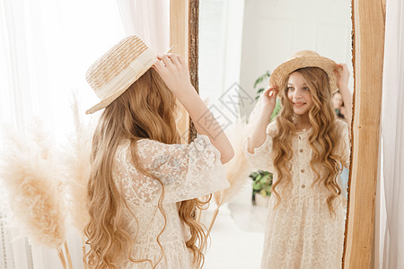 长发的美少女在镜子前戴上草帽 对金发女郎的自以为是的感觉帽子干草验收风格女孩装饰裙子青少年稻草女士图片