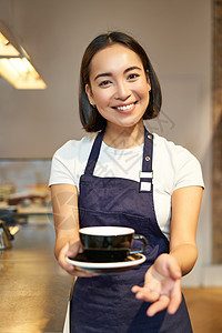 微笑美丽的亚洲女咖啡师 在咖啡馆工作 拿着茶 给客户点菜 穿着制服围裙服务员员工女孩企业家咖啡女性餐厅职员柜台店铺图片