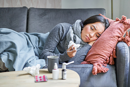 生病 悲伤的韩国女人躺在沙发上 感觉身体不适 感冒 流感和体温升高 看起来心烦意乱 正在服药药品温度毯子成人弱点过敏女性发烧感染图片