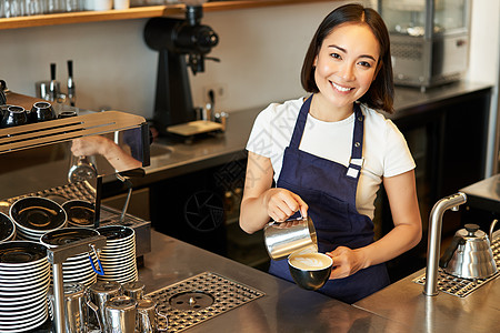 喝咖啡倒蒸牛奶的咖啡店工作人员 为拿铁艺术准备卡布奇诺Cappuccino 站在柜台后面的蓝色围裙员工职场服务员人士店铺广告食物图片