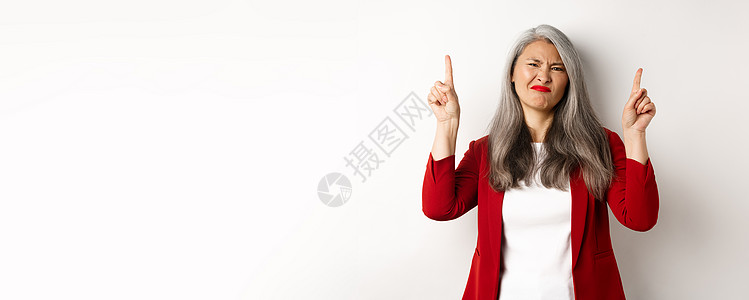 怀疑和失望的亚洲女商务人士举起手来指着手指 尖刻地指责并展示出糟糕的促销提议 站在白背景上站立广告化妆品套装技术雇主员工头发办公图片