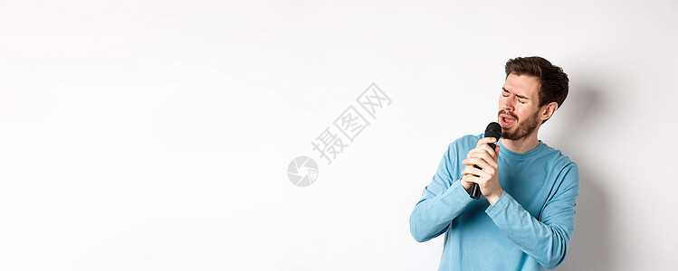罗马男子在卡拉OK的麦克风里唱歌 站在白色背景上胡子成人商业歌手工作室生活卡拉ok成功男人情绪背景图片