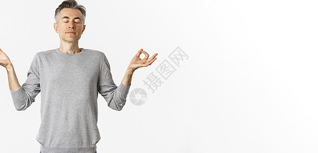 平静放松的中年男子肖像 自由呼吸空气 闭着眼睛冥想 双手横向伸展 在白色背景下练习瑜伽快乐成人商业胡须男性情感工作室发型促销毛衣图片
