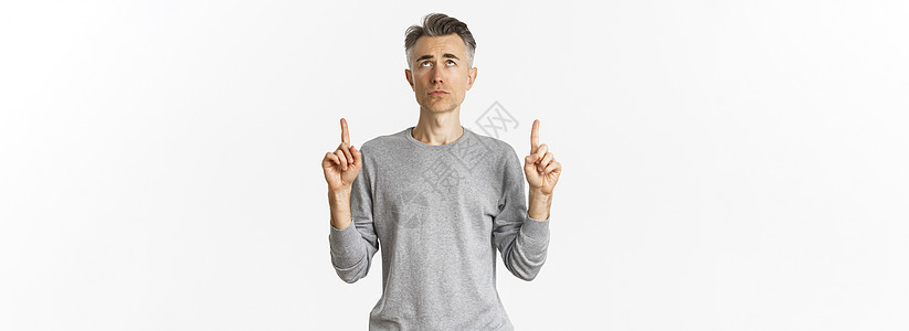 沮丧和犹豫不决的中年男子的肖像 看着烦乱 指着手指举起手来 站立在白背景上不安灰色标识胡须工作室成人男性促销广告毛衣发型图片
