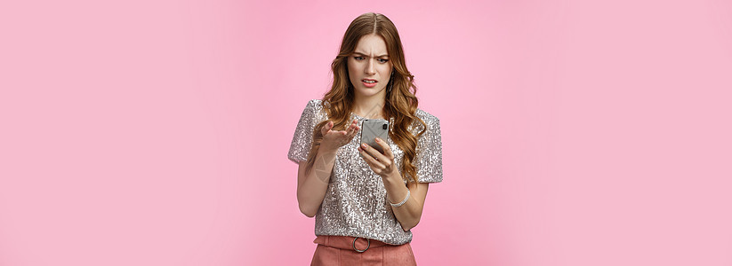 沮丧 生气的女人不断收到奇怪的信息 他们皱着眉头 烦躁地看着智能手机显示屏 指着恼怒的困惑 无法理解文章 粉红色背景派对欢呼互联图片
