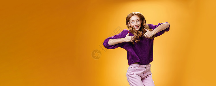 乐观快乐的鲜姜女孩开心地跳着 开心地竖起大拇指 赞同并在橙色墙上对超酷的想法或概念给予积极反馈雀斑紫色发型女朋友成人享受投标跳跃图片