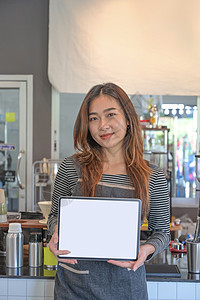 站在咖啡店的快乐女服务员肖像 用空展品展示数字平板电脑图片