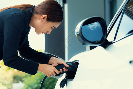 进步女性在家庭充电站为她的EV车补充补给技术杂交种汽油充值汽车排放电池能源收费女士图片