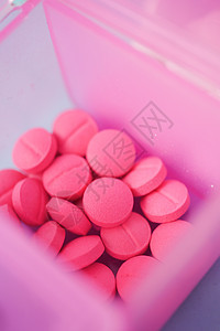 在桌上的药盒里 包着粉色止粉色医用药丸胶囊日程盒子药物药品剂量塑料背景图片
