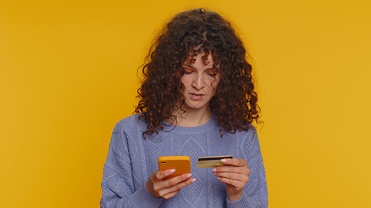 年轻女性在转账购买网上购物时使用信用卡和智能手机黄色金融网上购物贷款技术女孩塑料背景交易顾客图片
