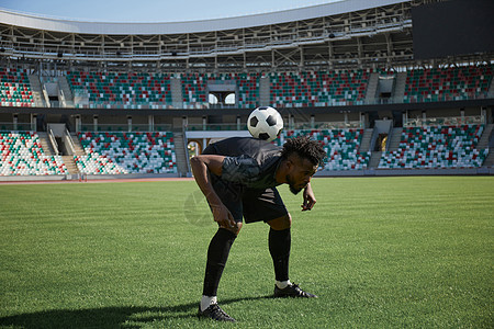 一个足球运动员正在训练 背着球握着球的后背图片