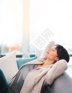 放松的年轻女人躺在沙发上 白天想在家睡午觉 但她却躺着 (笑声)图片